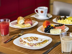 Desayuno servido con platos de comida, una taza de café y un vaso de jugo.