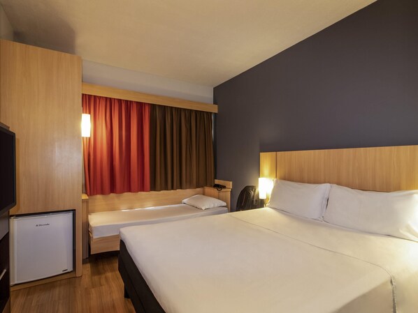 Une chambre d’hôtel avec un grand lit, un lit plus petit, un bureau, une chaise, une télévision et un mini-réfrigérateur.