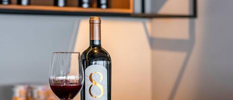 En flaska Rio Sol Gran Reserva 2017-vin står bredvid ett glas fyllt med rött vin, och i bakgrunden syns en hylla med vinflaskor.