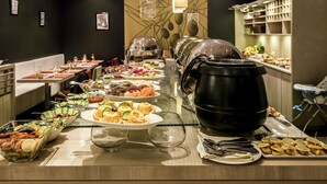 A buffet setup with various dishes, a large pot, and dining tables. - ibis Tlemcen (Tlemcen)