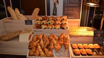 Une vitrine de boulangerie présentant différents types de pains et de viennoiseries, notamment des croissants et des baguettes.