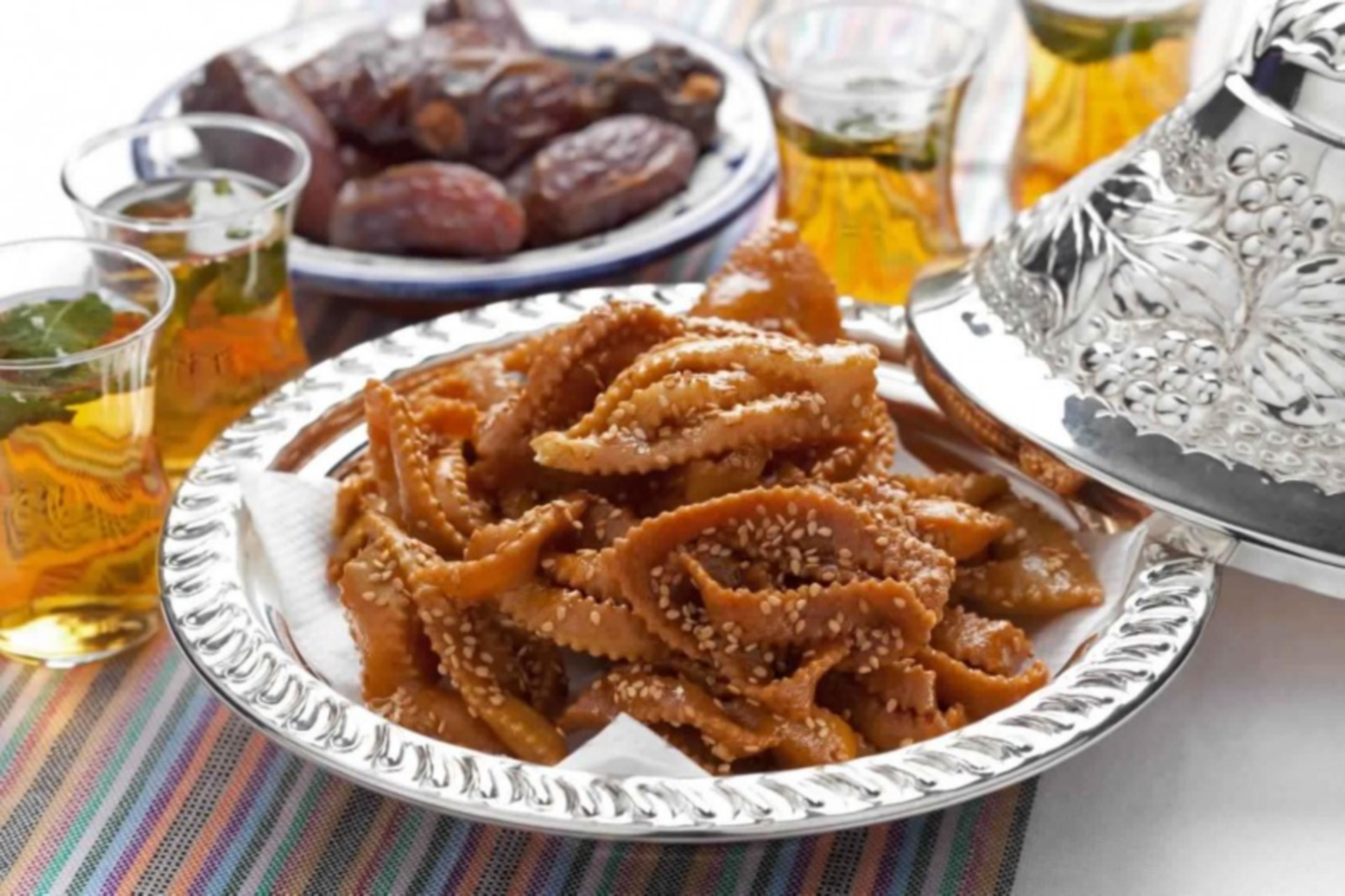 Un plat de fulles d'ametlles farcides, un bol de dàtils i un plat argentat amb un disseny floral.