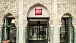 A hotel entrance with a red 'ibis Hotels' sign, two symmetrical archways, and a tiled floor. - ibis Tlemcen (Tlemcen)