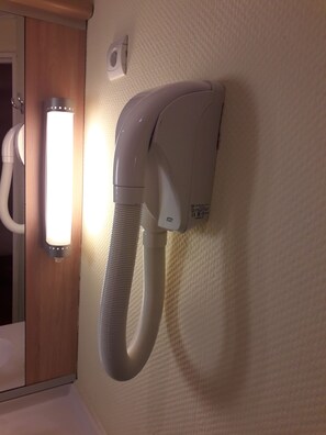 A wall-mounted vacuum cleaner with a flexible hose, a light fixture, and a power outlet. - ibis Tlemcen (Tlemcen)