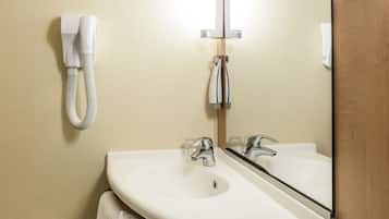 Une salle de bain avec un lavabo blanc, deux robinets, un miroir et un porte-serviettes.