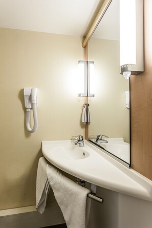 A bathroom with a white sink, two faucets, a mirror, and a towel rack. - ibis Tlemcen (Tlemcen)
