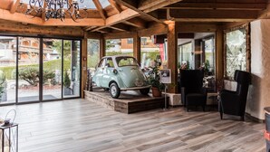 Un'auto d'epoca esposta in interni, con pavimento in legno, ampie finestre e un lampadario.