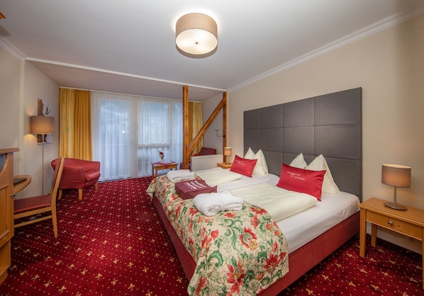 Habitación de hotel con una cama grande, dos mesitas de noche, una silla, un escritorio y una ventana con cortinas.