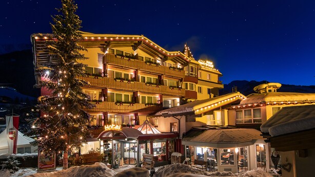 Un hotel a più piani con balconi, un albero di Natale e terreno innevato.