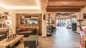 Un'ampia zona giorno con soffitto in legno, un divano, un tavolino e una libreria.