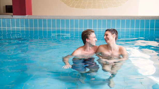 A swimming pool with tiled walls and a mural of a bathtub. - Vötter's Hotel (Kaprun)