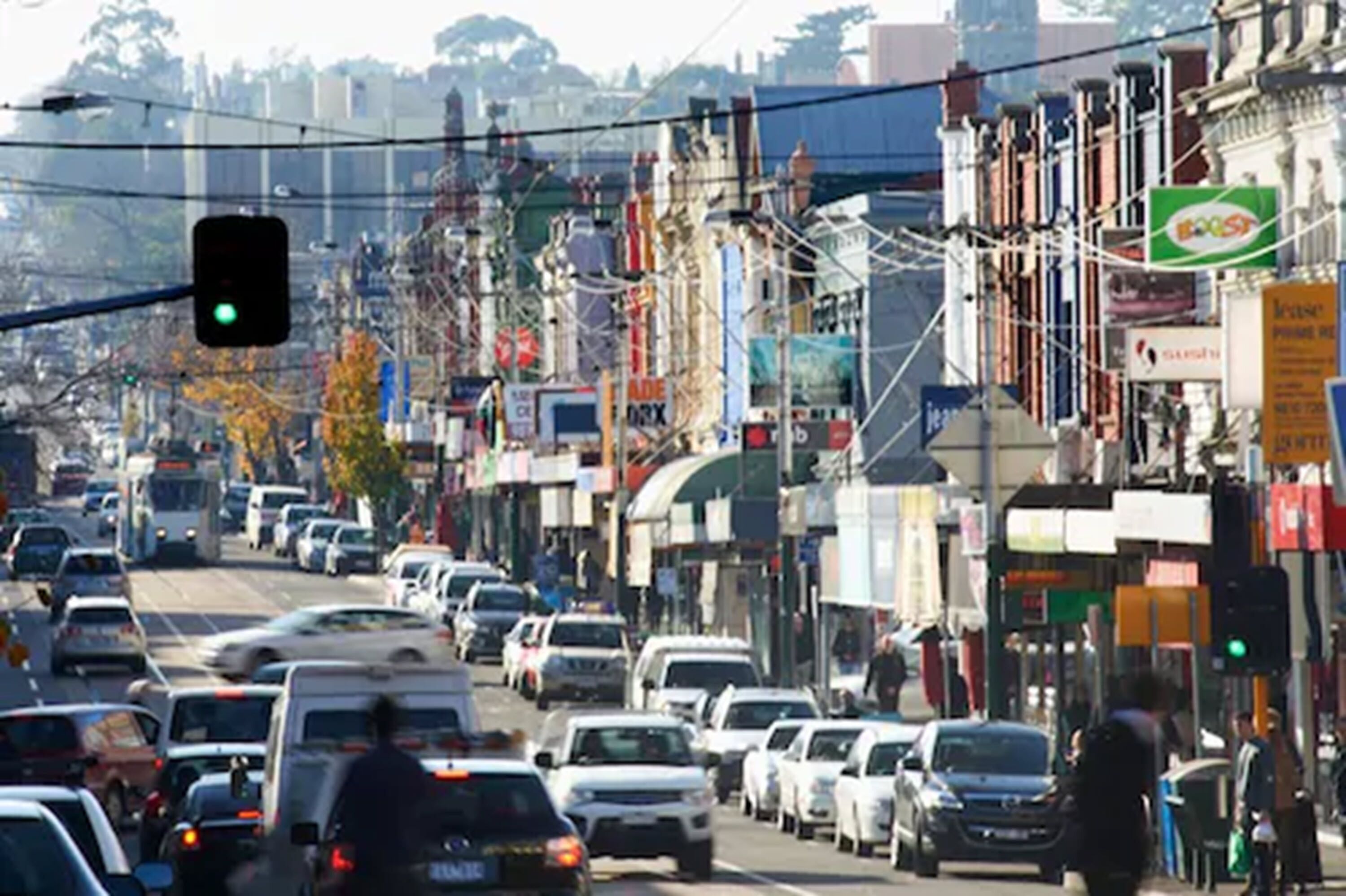 A busy urban street with various shops and vehicles.