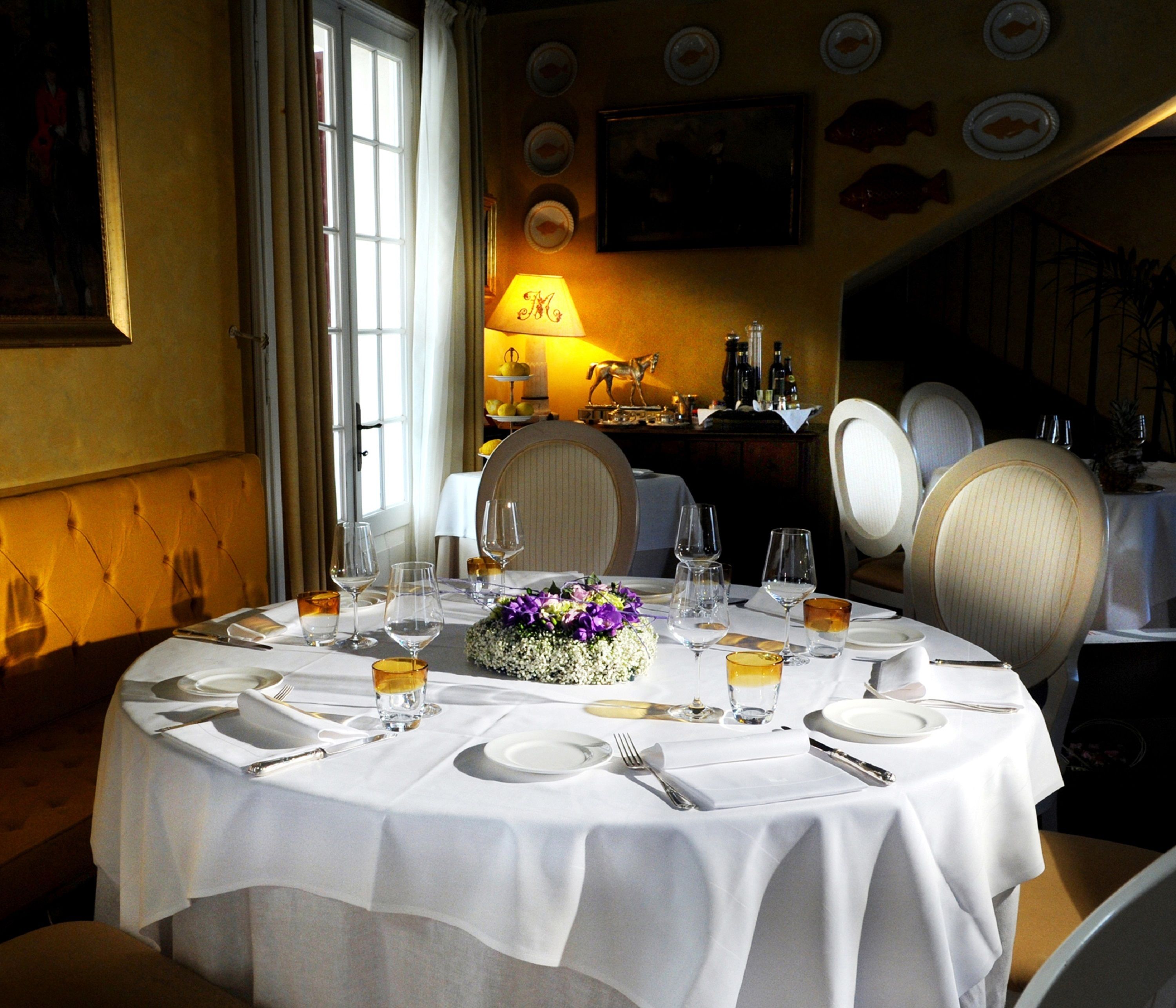 Une table à manger dressée pour quatre personnes, avec une nappe blanche, des assiettes, des verres et des couverts.