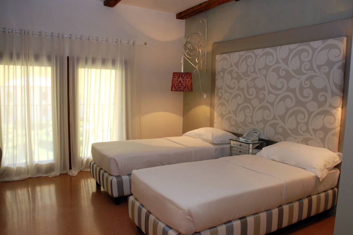 Ein Hotelzimmer mit zwei Betten, einem Nachttisch, einem Telefon und einer dekorativen Wandverkleidung.