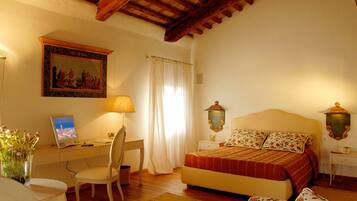 A bedroom with a bed, a desk with a chair, a lamp, a painting, and a nightstand with a lamp.