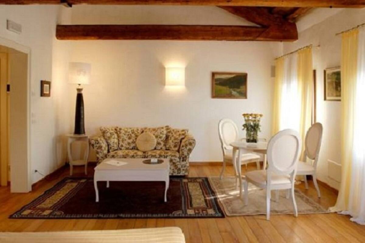 Ein gemütliches Wohnzimmer mit einer floralen Couch, einem Couchtisch und einem Essbereich mit Stühlen und Tisch.