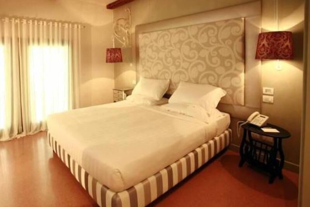 Ein Hotelzimmer mit einem großen Bett, einem Nachttisch mit Telefon und einem kleinen Tisch mit Lampe.