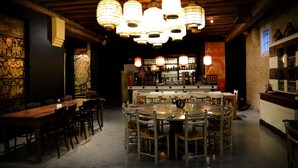 Een restaurant met een ronde eettafel, omringd door stoelen, een bar op de achtergrond en traditionele inrichting.