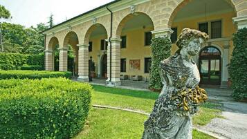 Ein klassizistisches Gebäude mit einer zentralen Statue in einem gepflegten Garten.