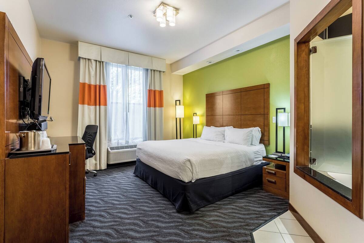 A hotel room with a bed, desk, chair, and a television.