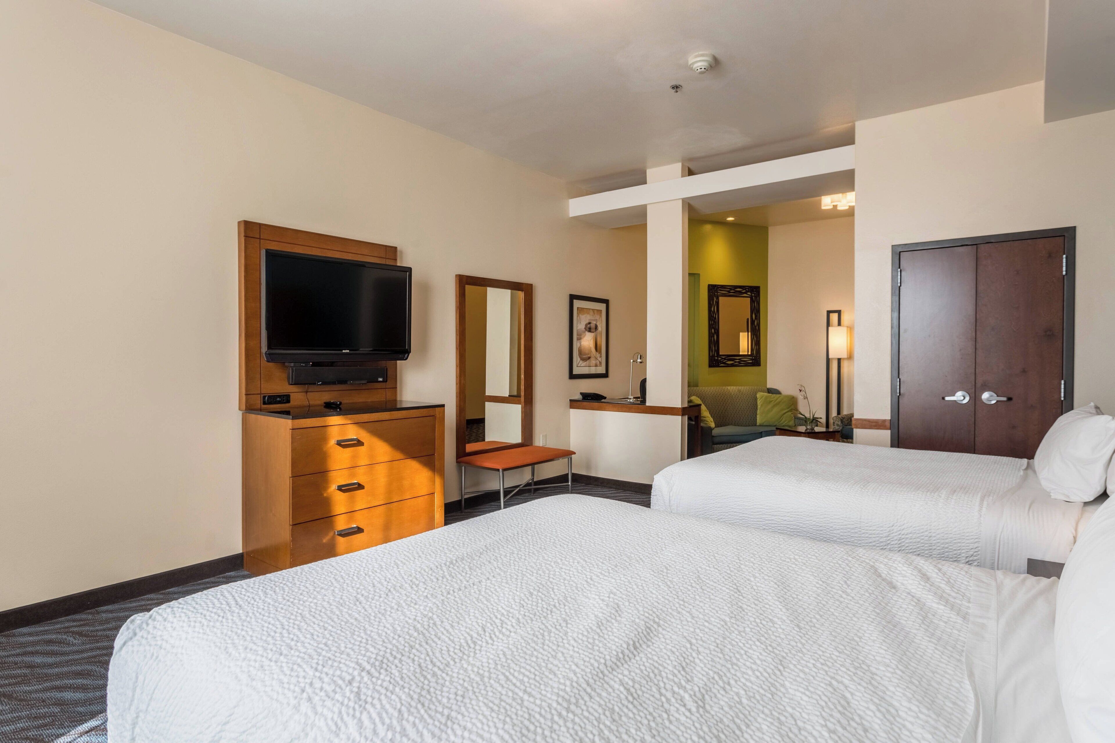 Una habitación de hotel con dos camas, televisión, escritorio y armario.