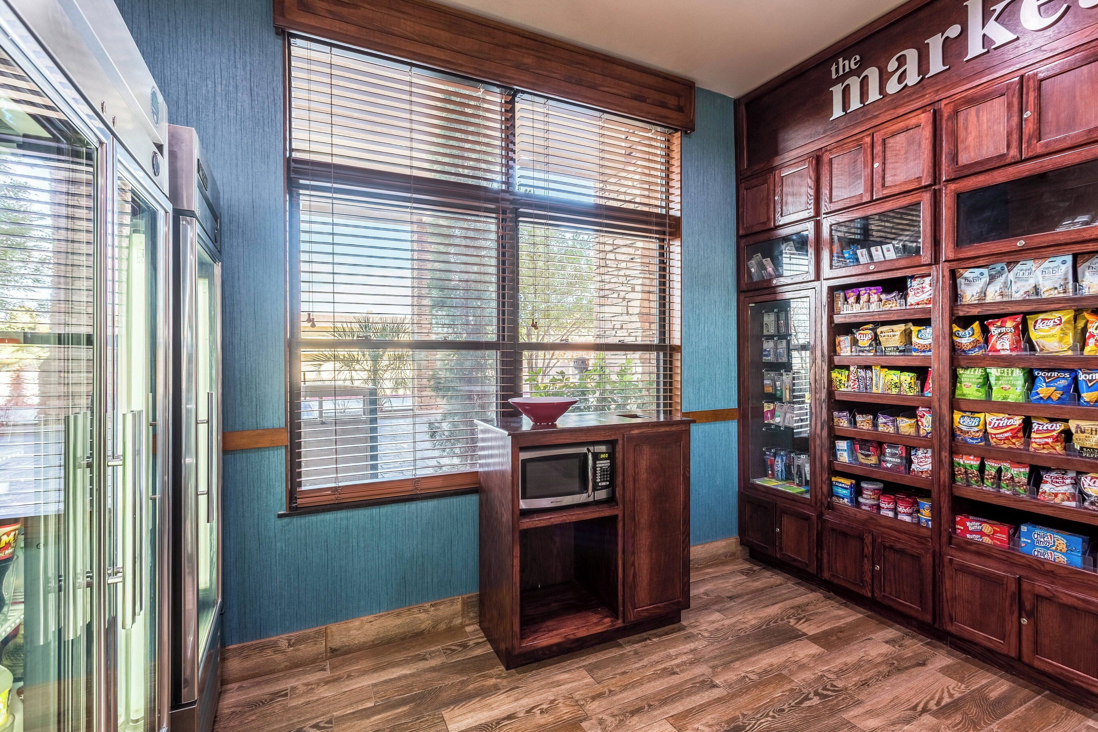 Una cocina con microondas, armarios de madera y una ventana con persianas.