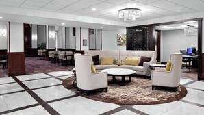 Eine moderne Lobby mit einer zentralen Sitzecke, einem Empfangsbereich und einem Computerarbeitsplatz.