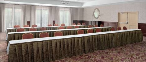 A conference room with a long table, rows of chairs, and a carpeted floor.