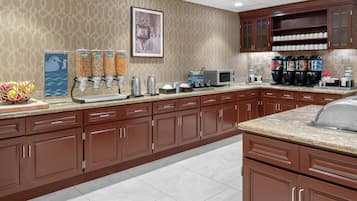 A kitchen with a coffee station, a microwave, and a coffee maker.
