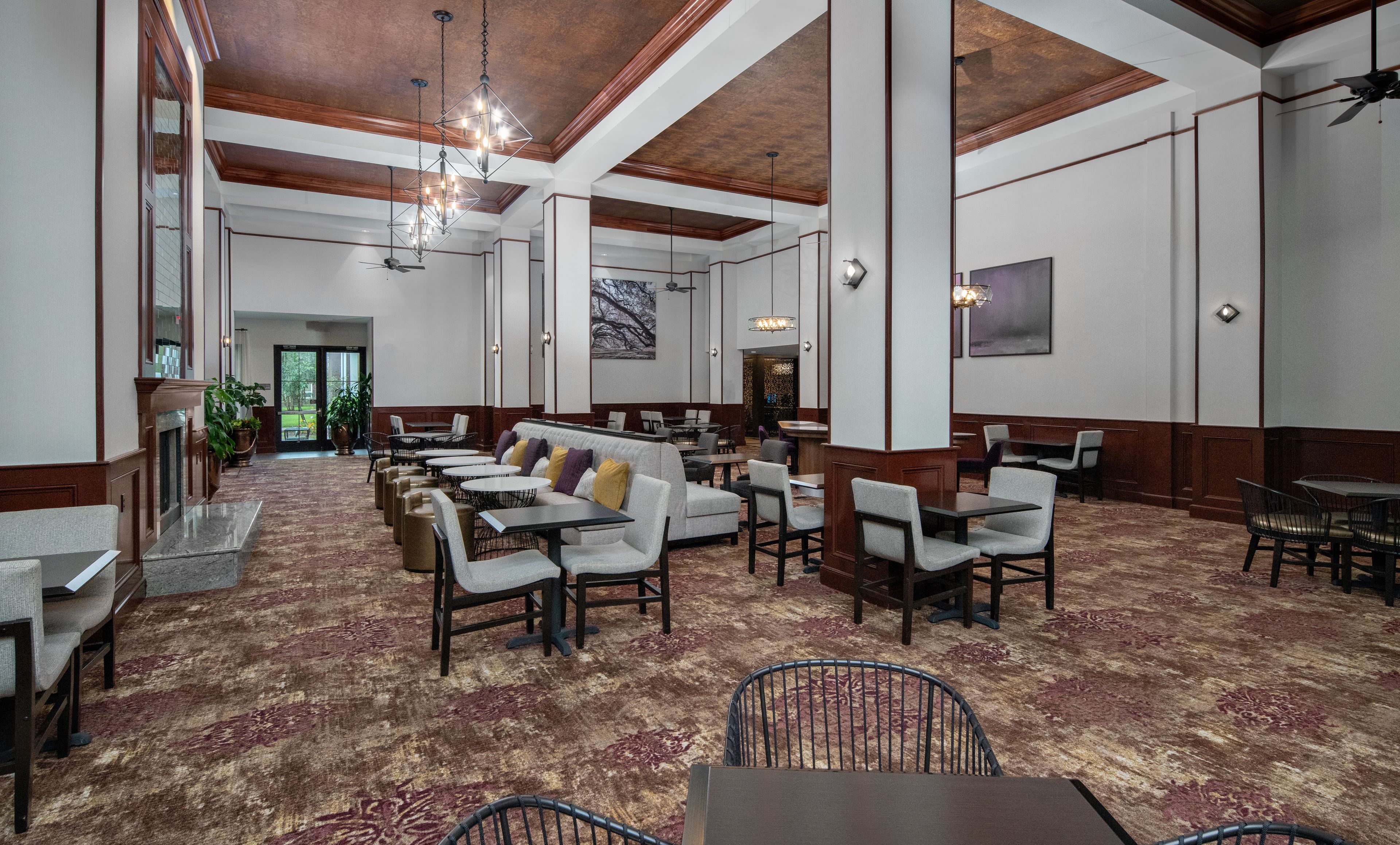 Un hall d’hôtel spacieux, doté de hauts plafonds, de lustres et d’un assortiment de différents types de sièges, notamment des canapés et des tables.