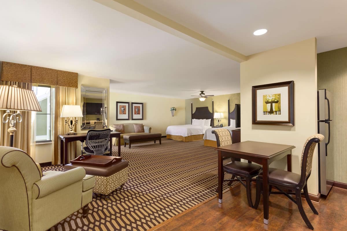 Una habitación de hotel con una cama, un escritorio, una silla, un sofá y una mesa de comedor.