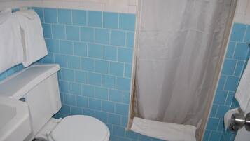Een badkamer met toilet, douchegordijn en blauwe tegels.