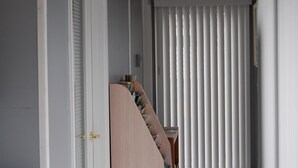 A narrow hallway with a closed door on the left, a white radiator above, and a bookshelf with magazines on the right. - Sea Breeze Inn (Ocean City)