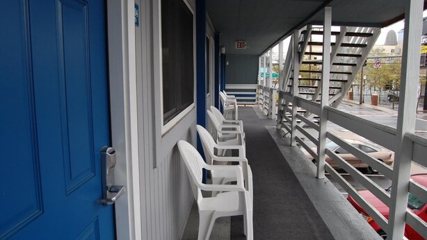 A covered outdoor seating area with white plastic chairs and a blue door. - Sea Breeze Inn (Ocean City)