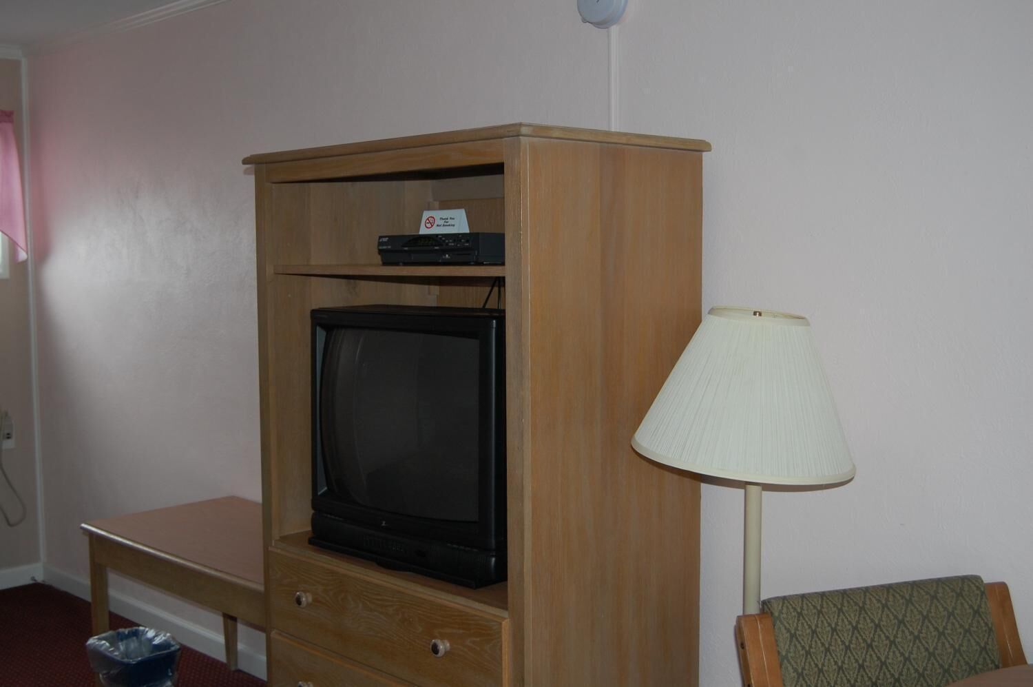 A room with a wooden cabinet containing a television and a small table.