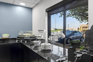 A modern kitchen with a glass partition, a coffee station, and a view of the parking area. - Sleep Inn & Suites Fort Campbell (Oak Grove)