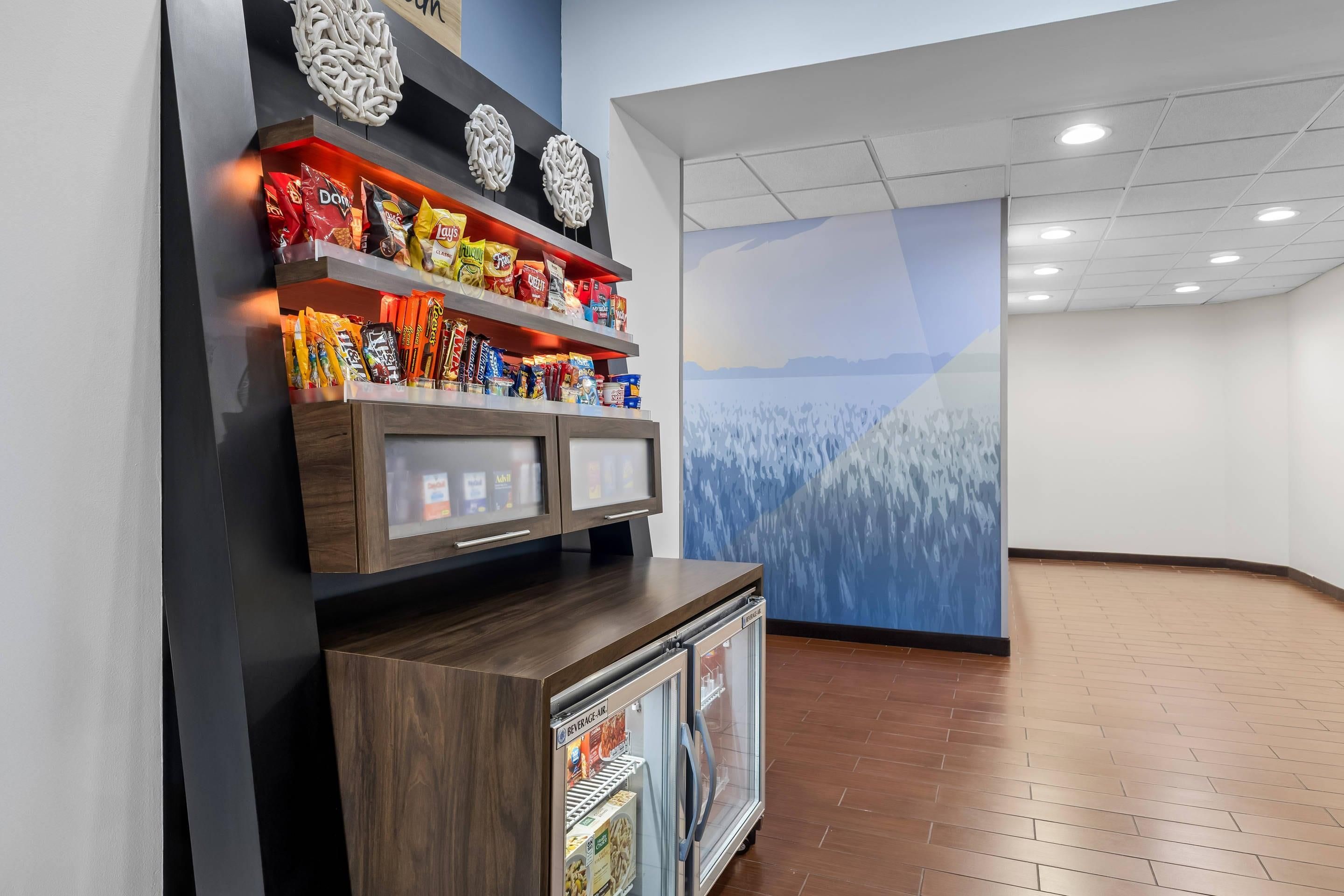 A snack display with various packaged foods, a beverage cooler, and a wall mural.