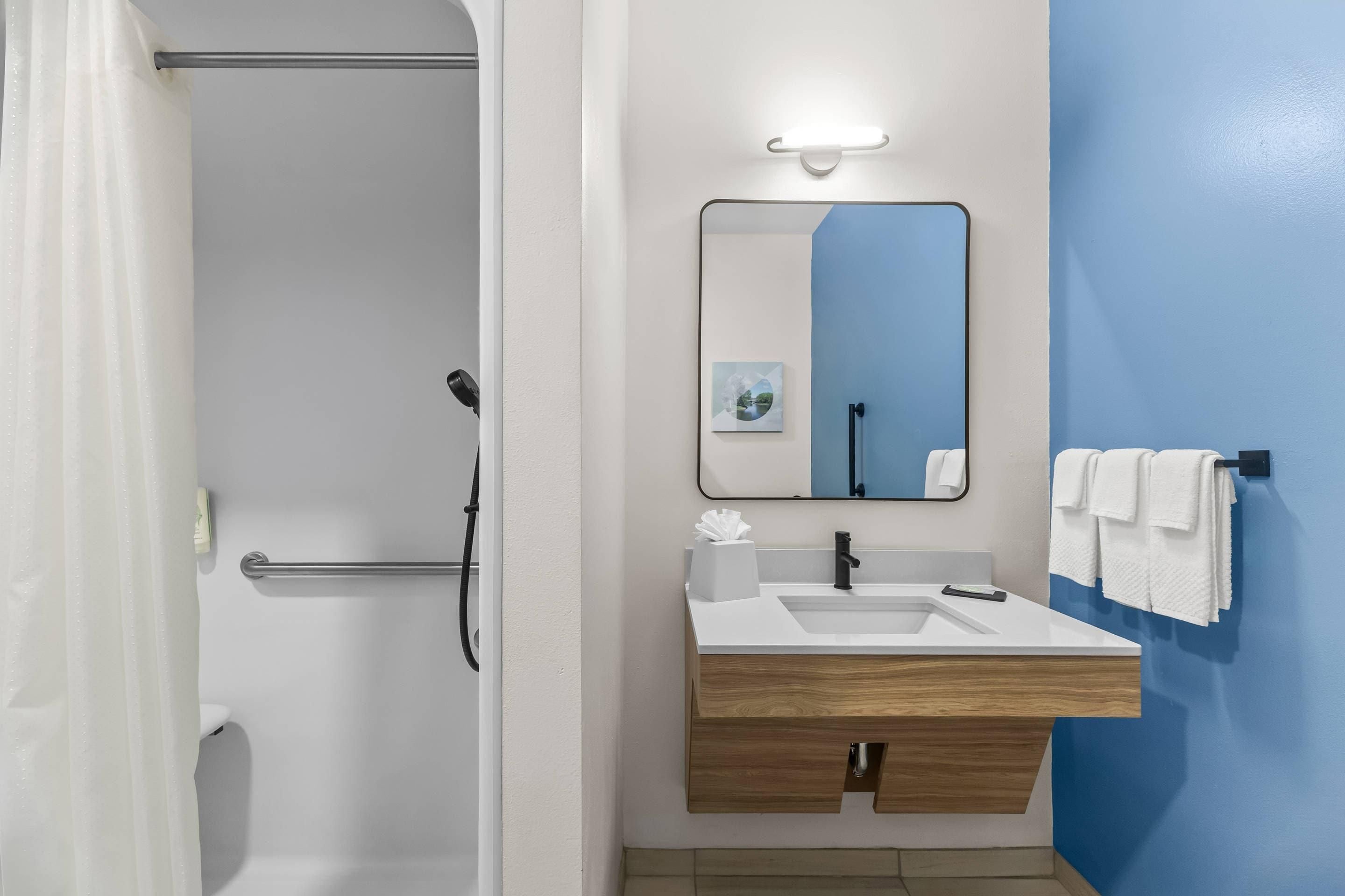 A bathroom with a shower, a sink with a mirror, and a towel rack.