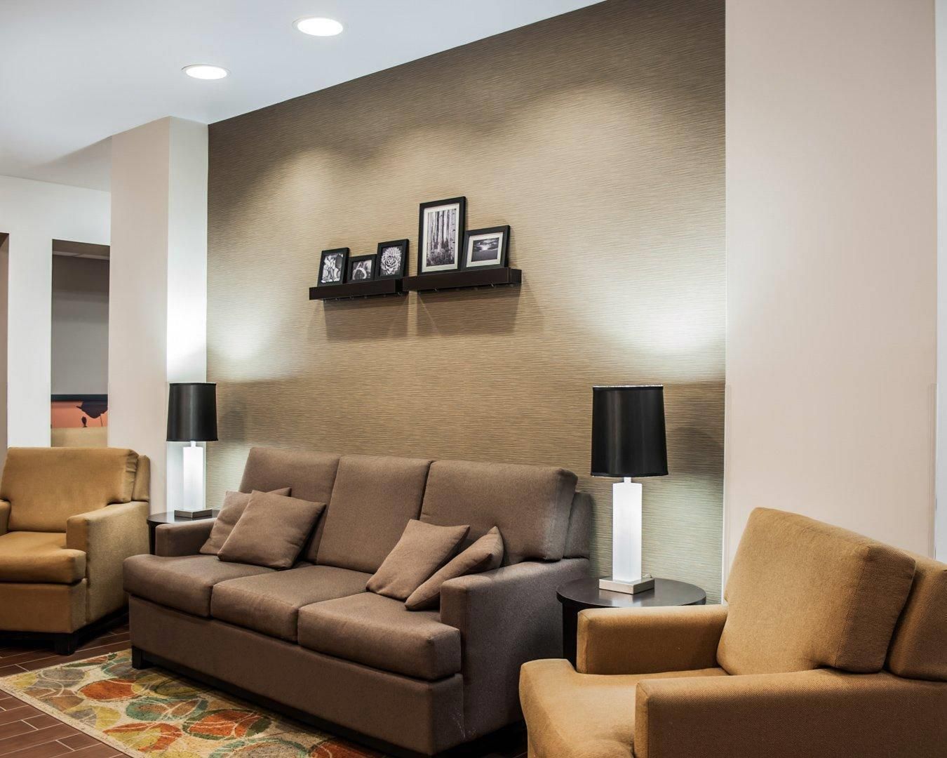 Una sala moderna con un sofá, dos sillones, una mesa de centro y un estante con marcos.