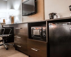 A modern kitchen with a built-in oven, a coffee maker, and a flat-screen TV mounted on the wall.
