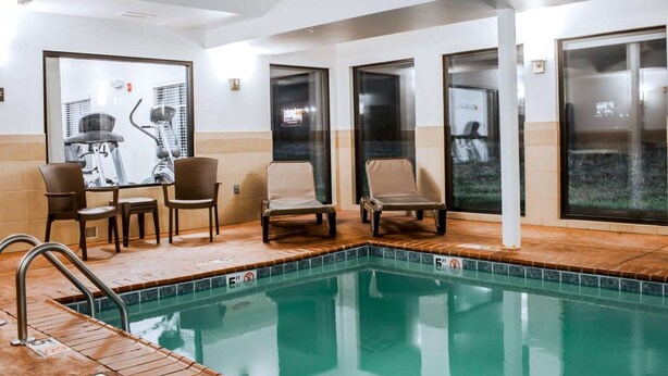 A pool area with exercise equipment, chairs, and large windows.