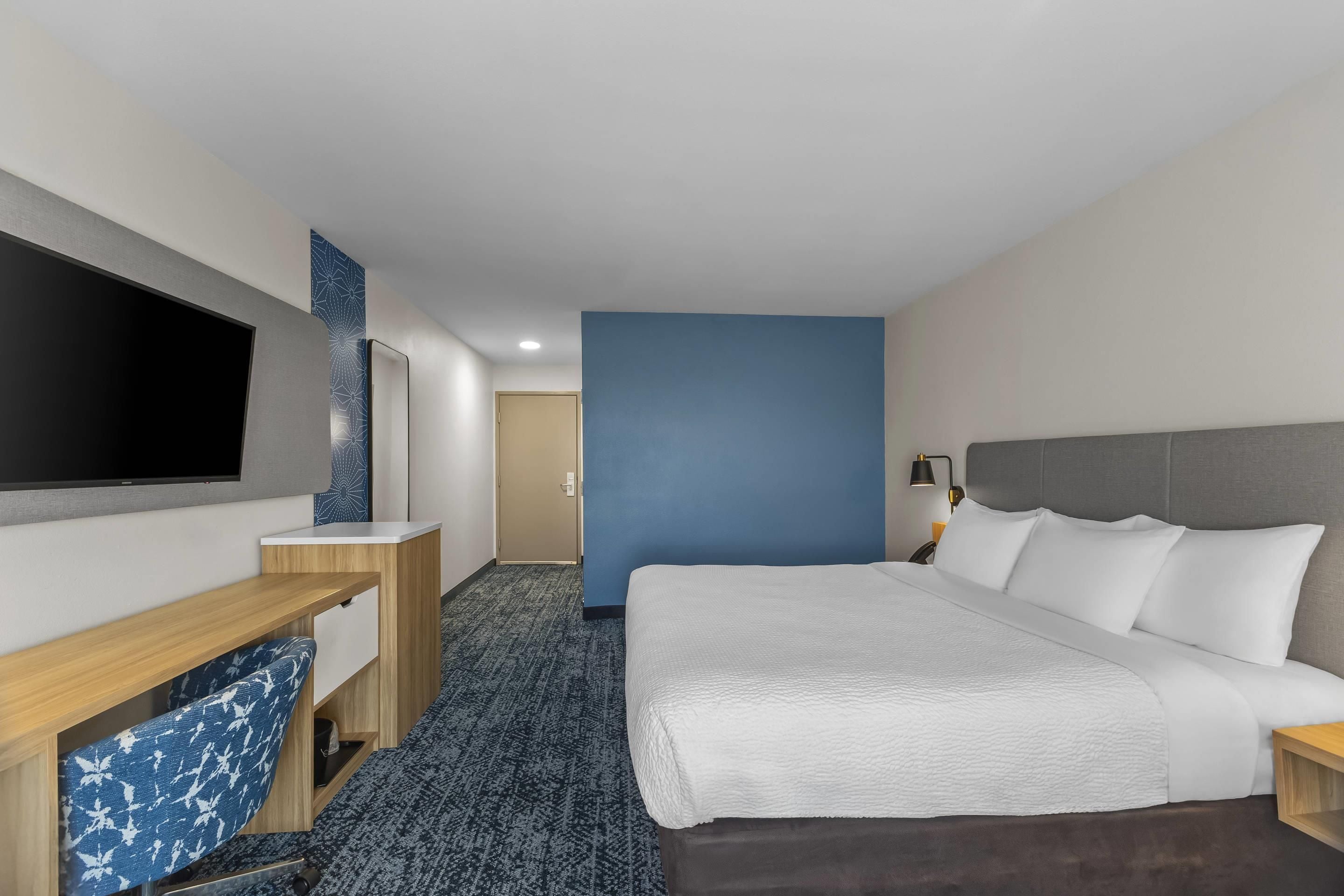 A hotel room with a bed, a TV, a desk, and a wardrobe.