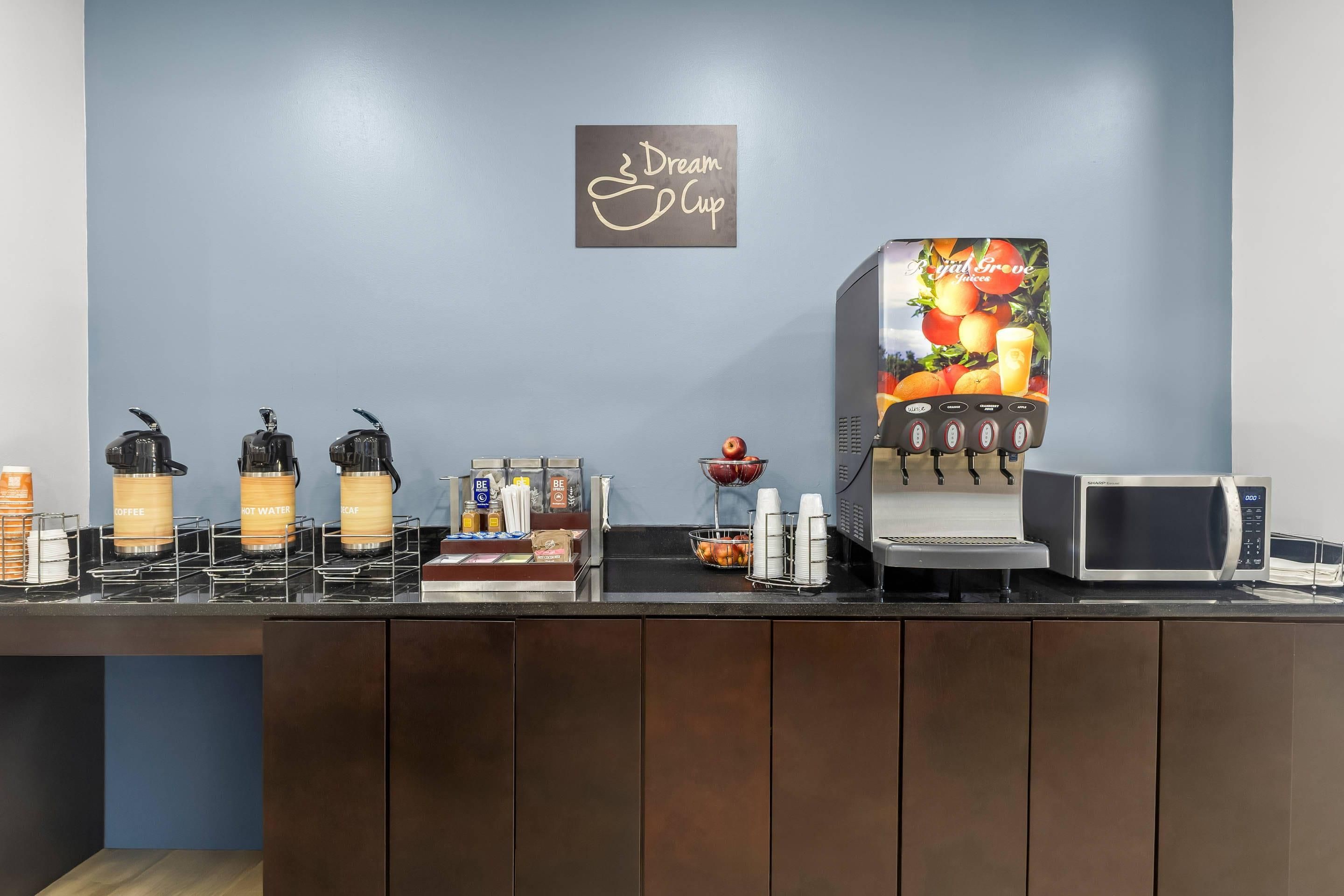 A coffee station with various drink dispensers, a microwave, and a juice dispenser.