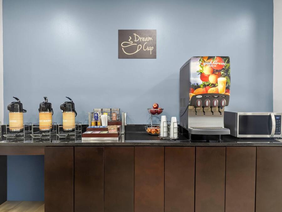 A coffee station with various drink dispensers, a microwave, and a juice dispenser.