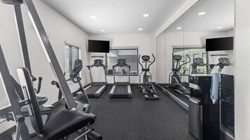 A gym with treadmills, elliptical machines, and a weight bench.