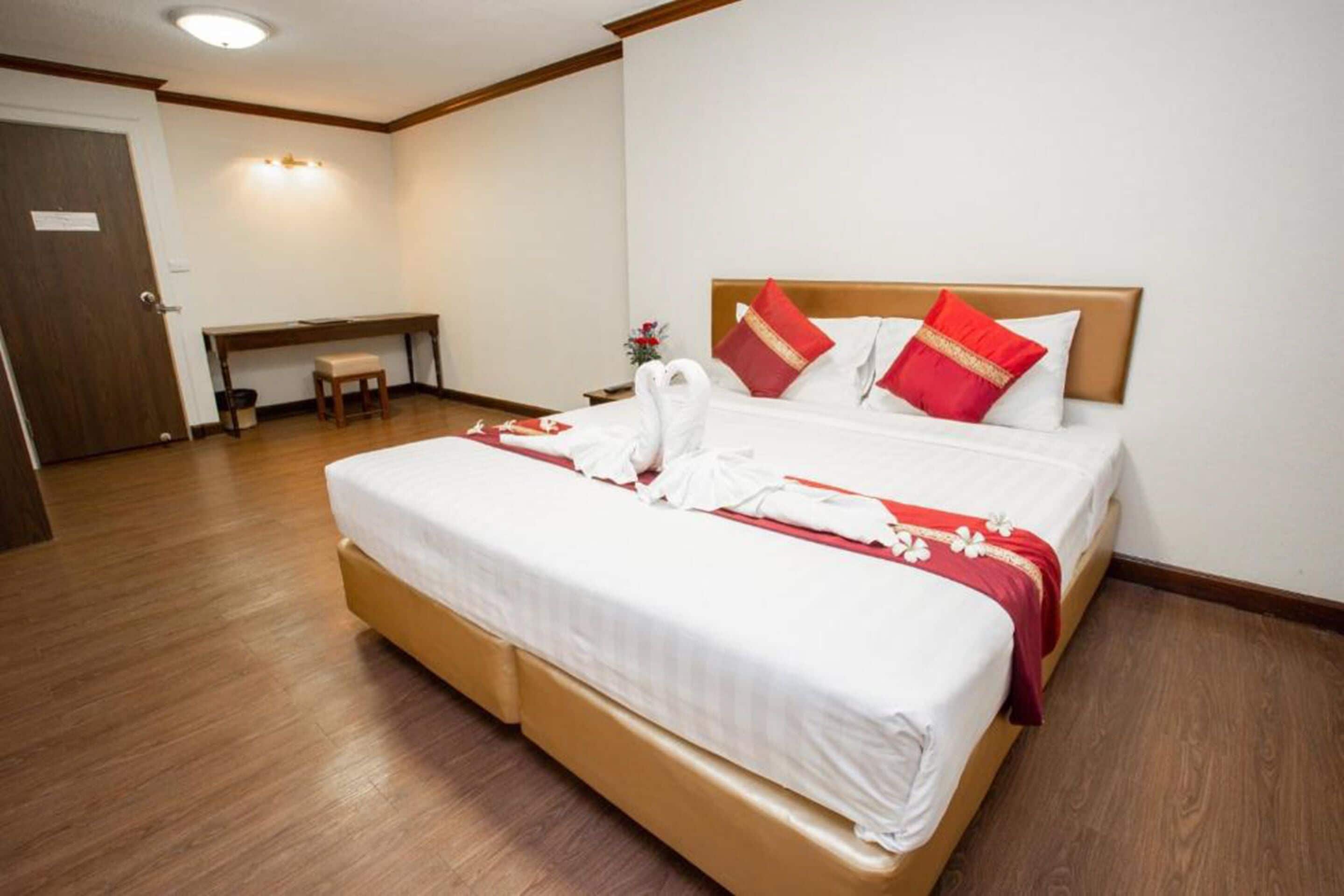 A hotel room with a large bed, a bedside table, and a bench.