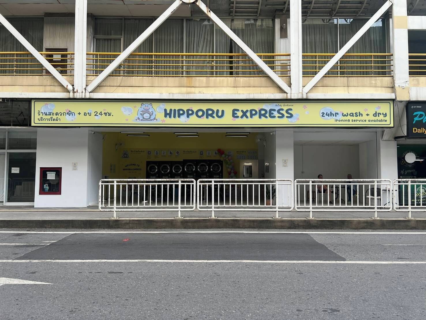 Un bâtiment avec une enseigne jaune indiquant « HIPPO EXPRESS », proposant des services de blanchisserie et de nettoyage à sec ouverts 24 heures sur 24.