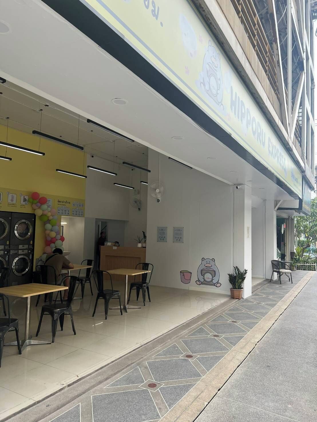 A restaurant with outdoor seating, a visible counter, and a sign above the entrance.