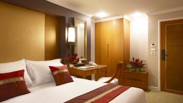 Une chambre d’hôtel avec un grand lit, un bureau, une chaise, une armoire et une porte.