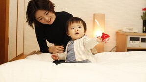 Un niño en una cama con una mesita de noche cerca.
